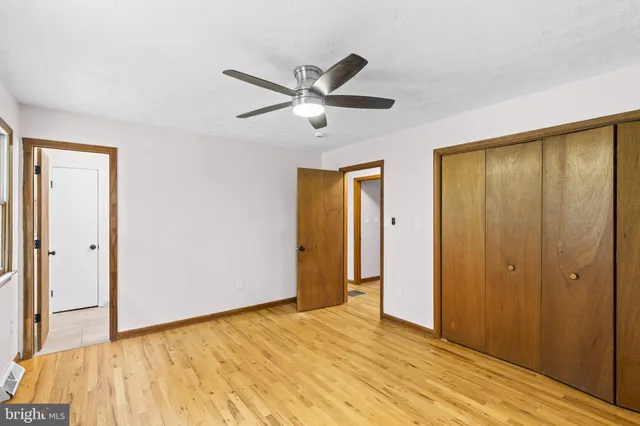 a view of empty room with wooden floor and fan