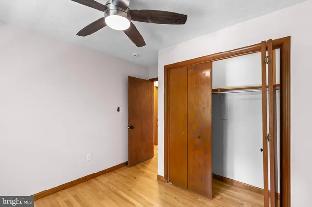 a view of empty room with wooden floor and fan