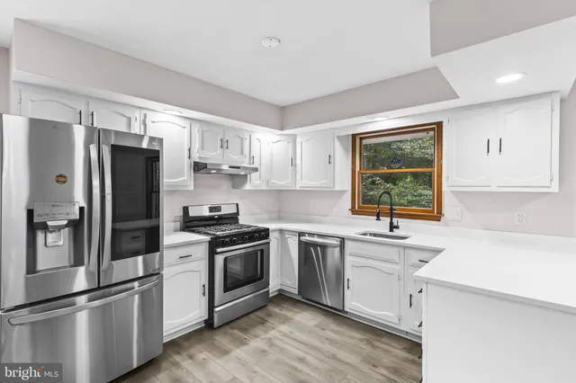 a kitchen with stainless steel appliances white cabinets and a refrigerator