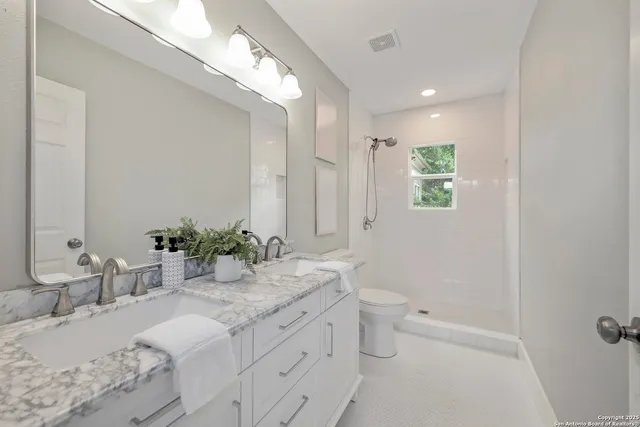 a bathroom with a granite countertop sink a large mirror a toilet and a bathtub