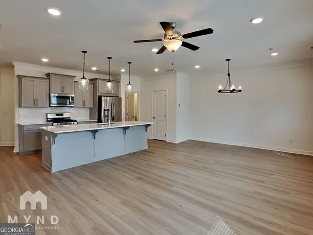 an open kitchen with kitchen island white cabinetry and stainless steel appliances