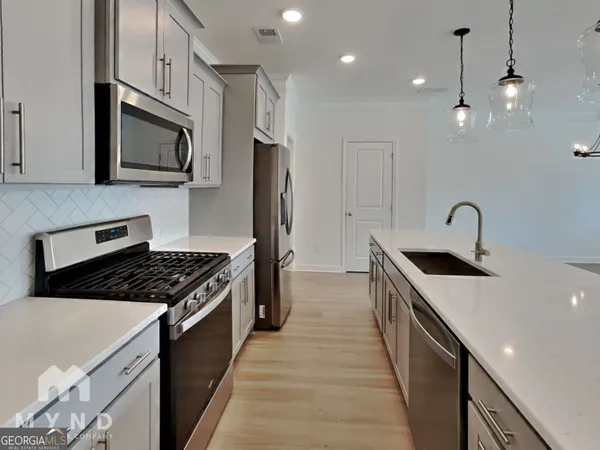 a kitchen with stainless steel appliances granite countertop a sink a stove oven a refrigerator with wooden cabinets and floor