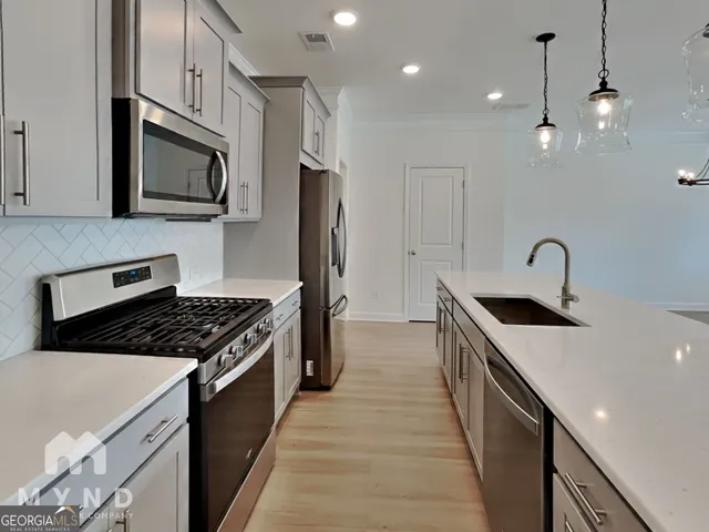 a kitchen with stainless steel appliances granite countertop a sink a stove oven a refrigerator with wooden cabinets and floor