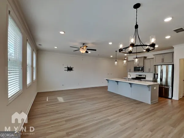 a view of a room with kitchen island stainless steel appliances wooden floor and large windows