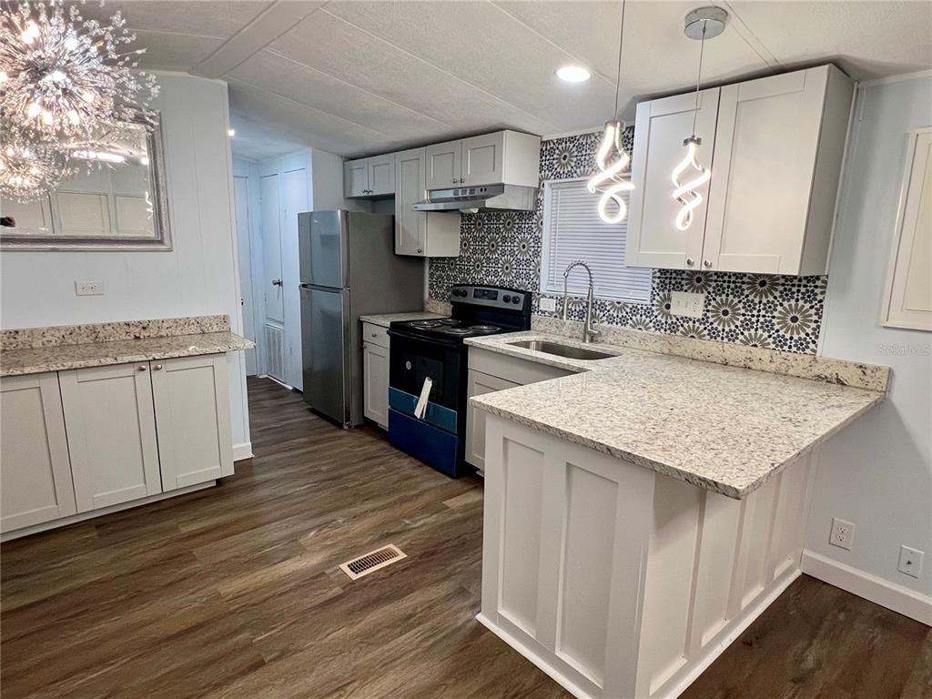 3000 Clarcona Road, Unit 410 Apopka, FL 32703 - Photo 8 of 11 a kitchen with stainless steel appliances granite countertop a sink stove and wooden floor
