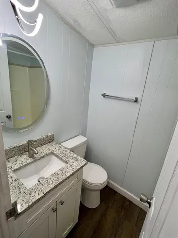 a bathroom with a granite countertop toilet sink and mirror