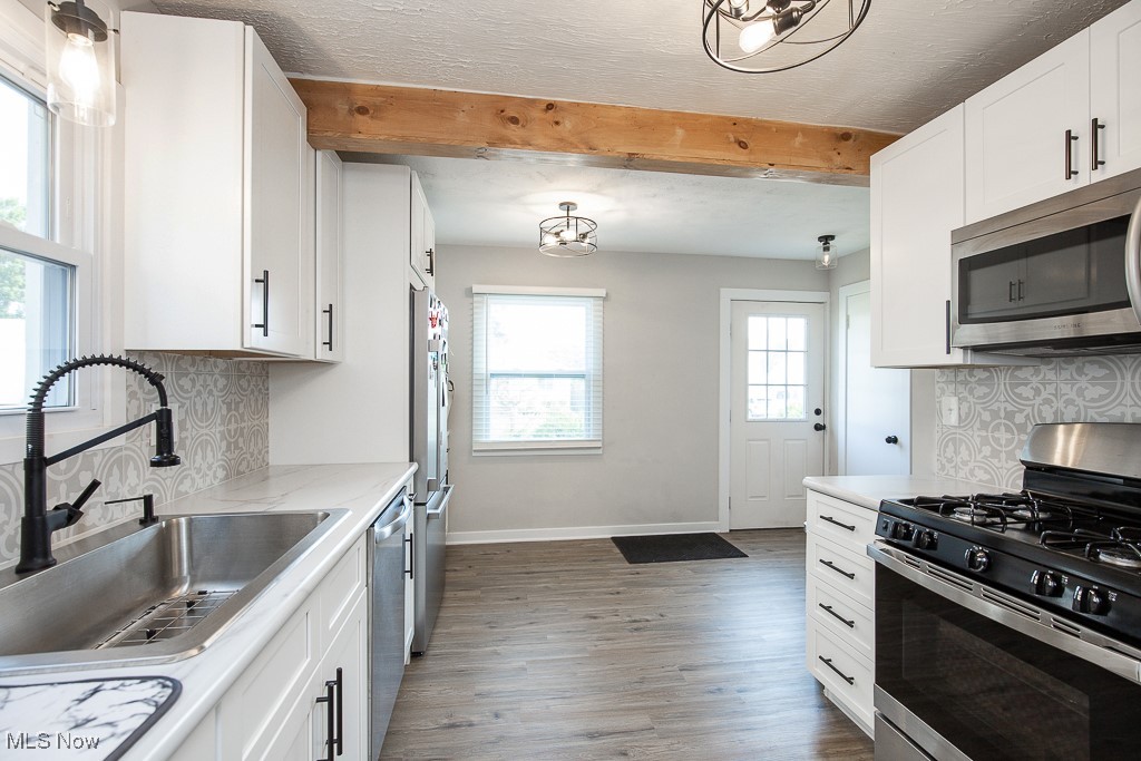 5607 Ridgewood Avenue Parma, OH 44129 - Photo 9 of 23 Kitchen with beamed ceiling, appliances with stainless steel finishes, a healthy amount of sunlight, and hardwood / wood-style flooring