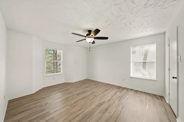 a view of empty room with wooden floor and fan