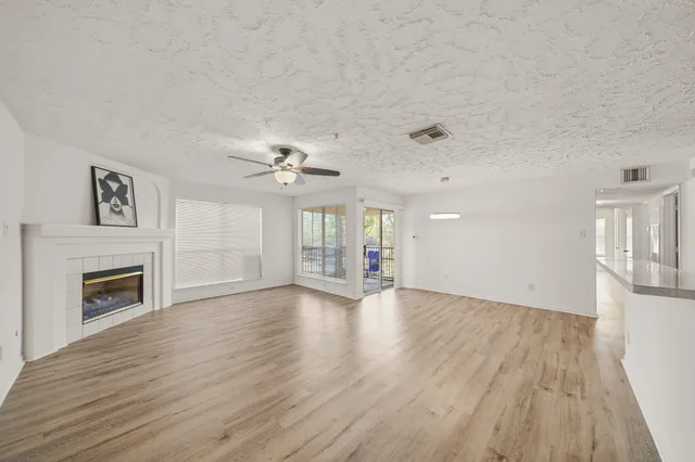 a view of an empty room with wooden floor and a fireplace