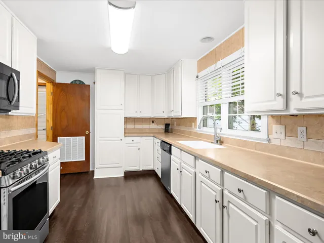 a kitchen with stainless steel appliances granite countertop a refrigerator a stove and a sink with wooden floor