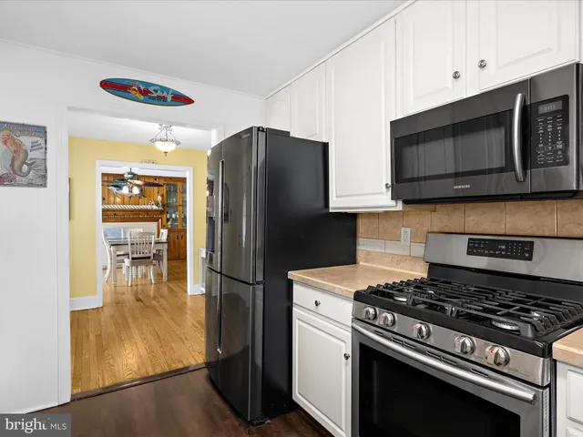 a living room with stainless steel appliances granite countertop furniture and a wooden floor