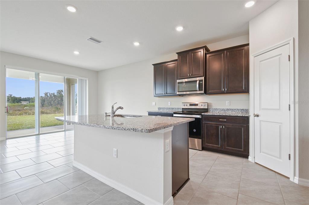 3827 Sunny Spring Street Plant City, FL 33565 - Photo 14 of 57 a kitchen with stainless steel appliances granite countertop a stove sink and cabinets