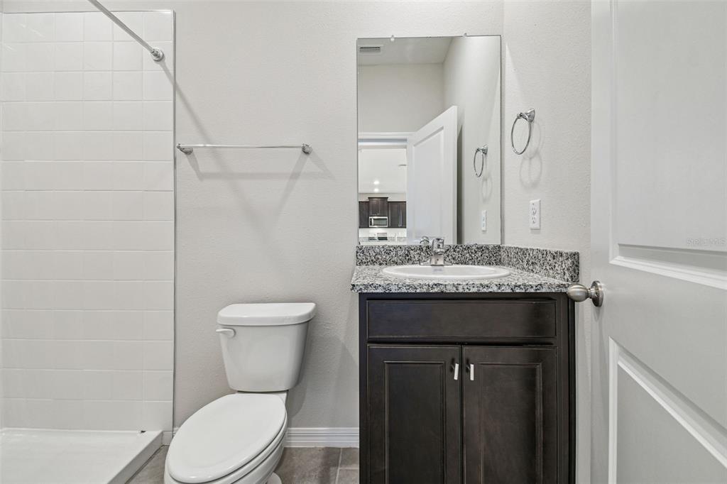 3827 Sunny Spring Street Plant City, FL 33565 - Photo 18 of 57 a bathroom with a granite countertop toilet a sink and a mirror