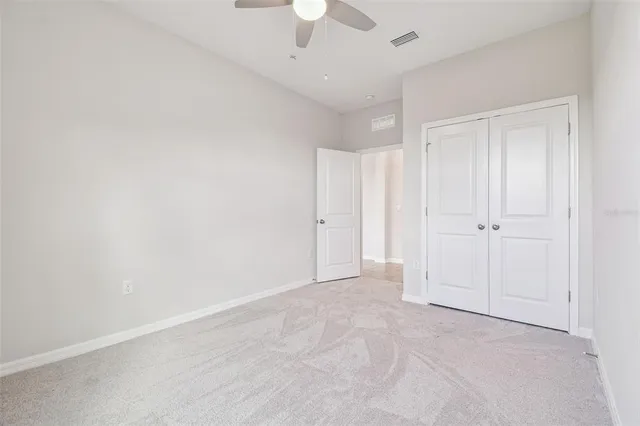 an empty room with ceiling fan and windows