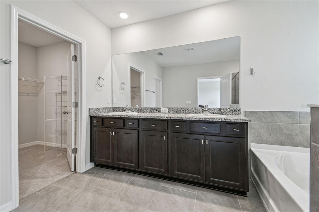 3827 Sunny Spring Street Plant City, FL 33565 - Photo 32 of 57 a bathroom with a granite countertop sink two mirror and a bathtub