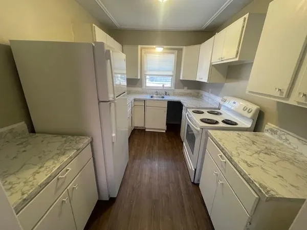 a kitchen with a refrigerator a sink and wooden floor