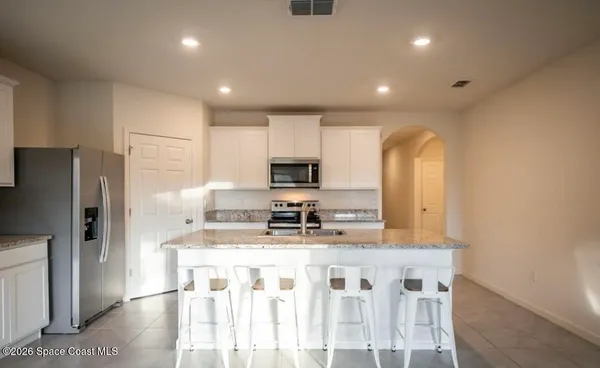 a kitchen with stainless steel appliances kitchen island granite countertop a refrigerator and a sink