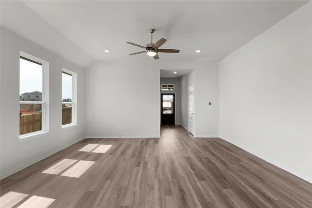 an empty room with windows and ceiling fan