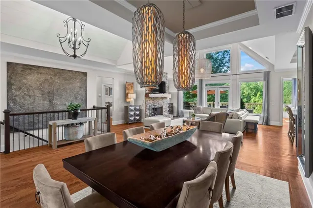 a dining room with wooden floor a chandelier a wooden table and chairs
