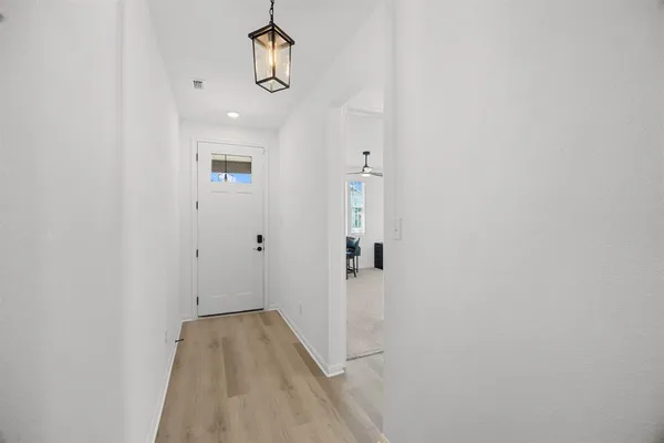 a view of a hallway with wooden floor and chandelier
