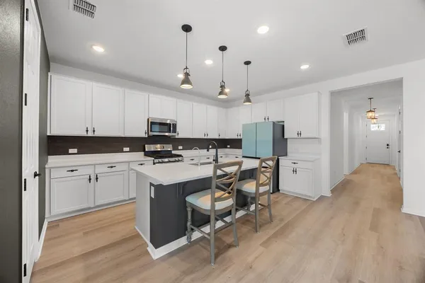 a kitchen with kitchen island white cabinets and stainless steel appliances