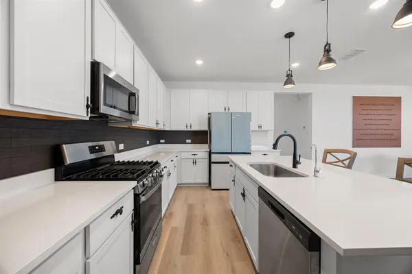 a kitchen with stainless steel appliances a sink a stove a refrigerator and cabinets