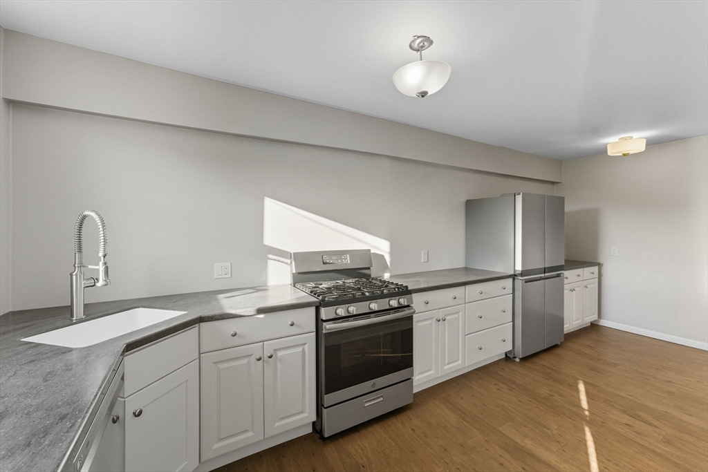 130 Broadway Fall River, MA 02721 - Photo 8 of 42 a kitchen with granite countertop a stove top oven sink and cabinets