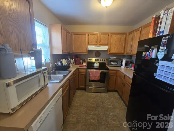 a kitchen with kitchen island granite countertop a sink a stove top oven a refrigerator a sink dishwasher with a dining table and chairs