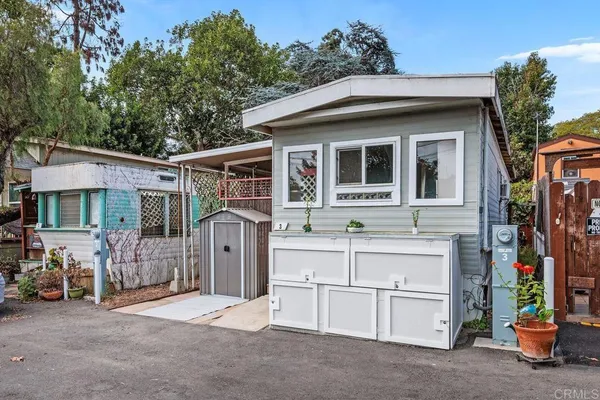 a view of a house with a barbeque and large trees