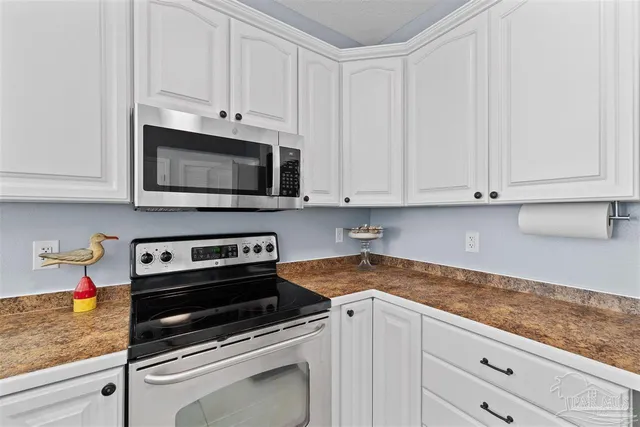 a kitchen with granite countertop white cabinets and stainless steel appliances