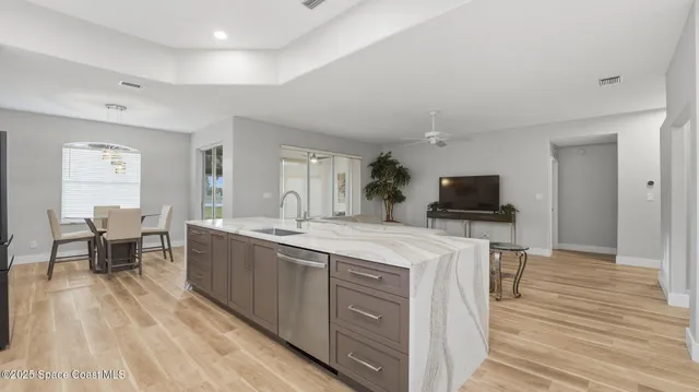 a large living room with stainless steel appliances granite countertop furniture a fireplace and a flat screen tv