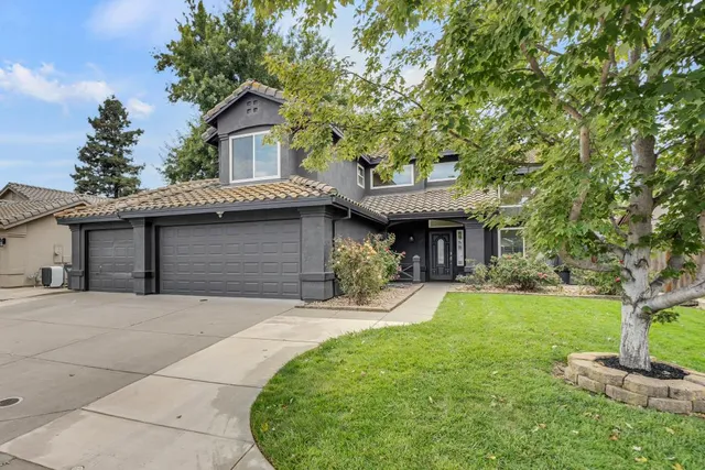 a front view of a house with a garden and trees