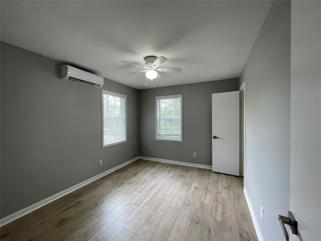 a view of an empty room with a window and wooden floor
