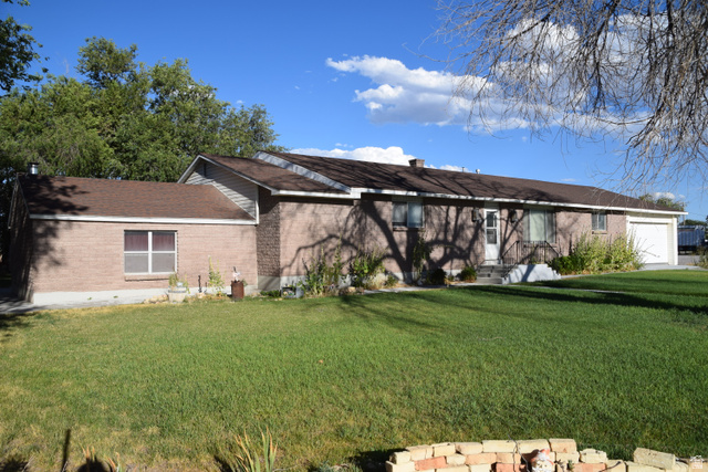 4265 South 4000 W Road Delta, UT 84624 - Photo 3 of 32 Brick exterior with an attached garage, featuring a front lawn and mature trees