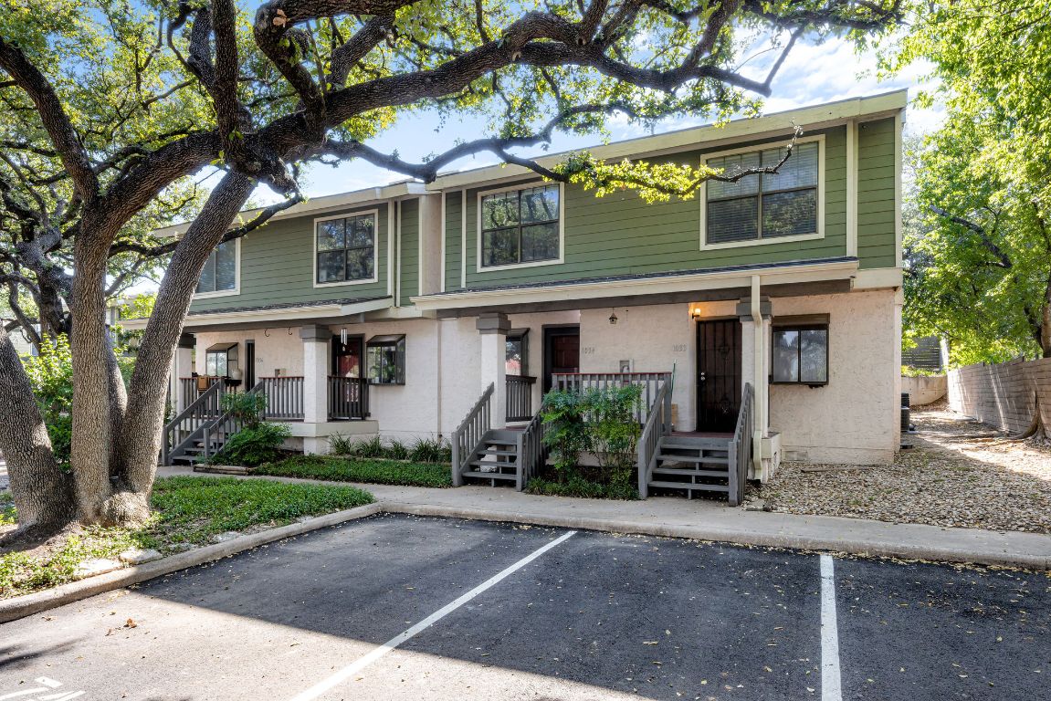 View of front of home with uncovered parking, stairway, and covered porch