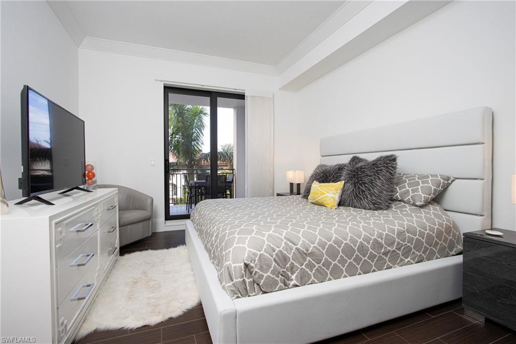 1035 3rd Avenue South, Unit 303 Naples, FL 34102 - Photo 11 of 26 a bedroom with a bed and a flat screen tv