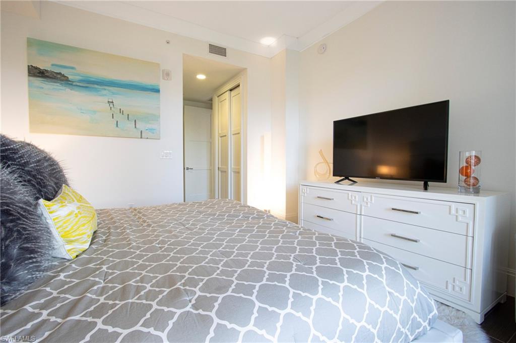 1035 3rd Avenue South, Unit 303 Naples, FL 34102 - Photo 12 of 26 a bedroom with a bed and a flat screen tv in it