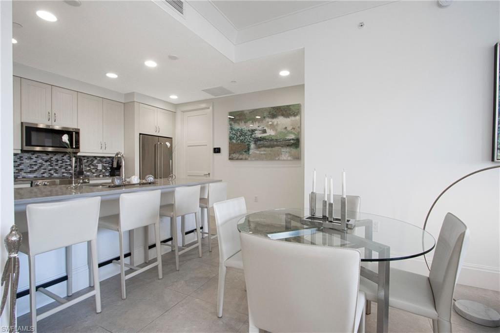 1035 3rd Avenue South, Unit 303 Naples, FL 34102 - Photo 6 of 26 a kitchen with a dining table chairs and refrigerator