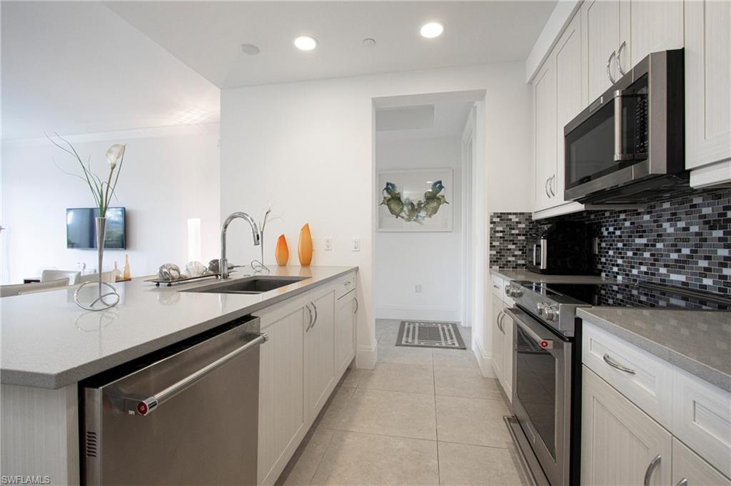1035 3rd Avenue South, Unit 303 Naples, FL 34102 - Photo 8 of 26 a kitchen with stainless steel appliances granite countertop a sink and stove top oven
