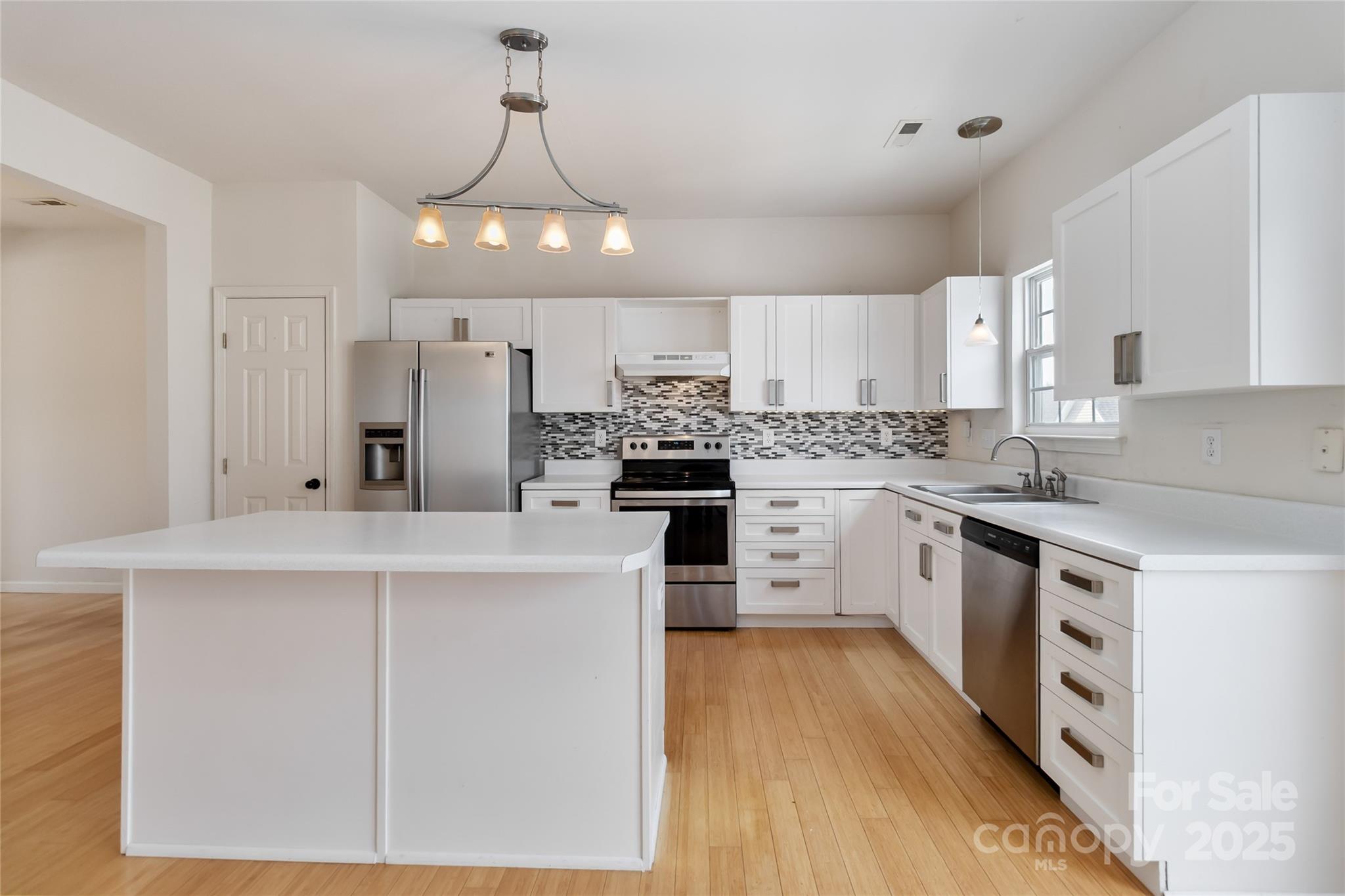 6825 Creft Circle, Unit 49 Indian Trail, NC 28079 - Photo 6 of 21 a kitchen with stainless steel appliances a stove a sink dishwasher a refrigerator and white cabinets with wooden floor