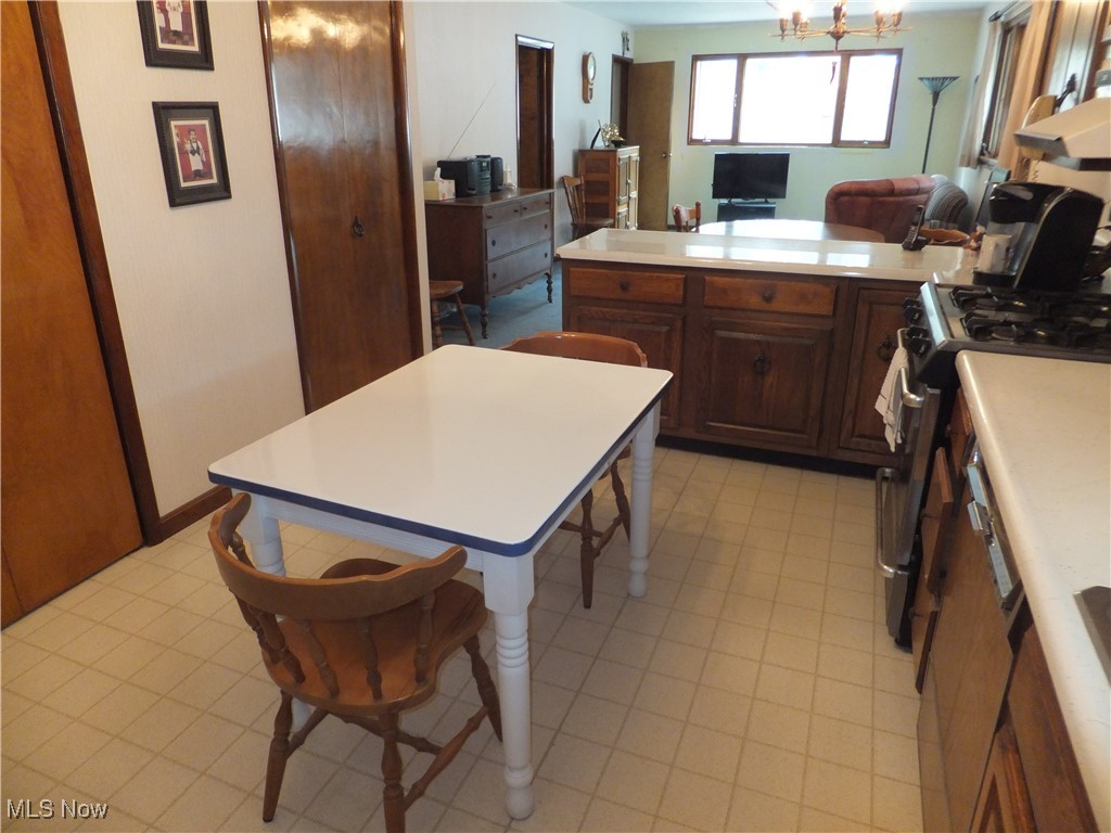 5113 Snow Road Cleveland, OH 44134 - Photo 8 of 40 Kitchen with stainless steel gas range, exhaust hood, a center island, a notable chandelier, and a kitchen bar