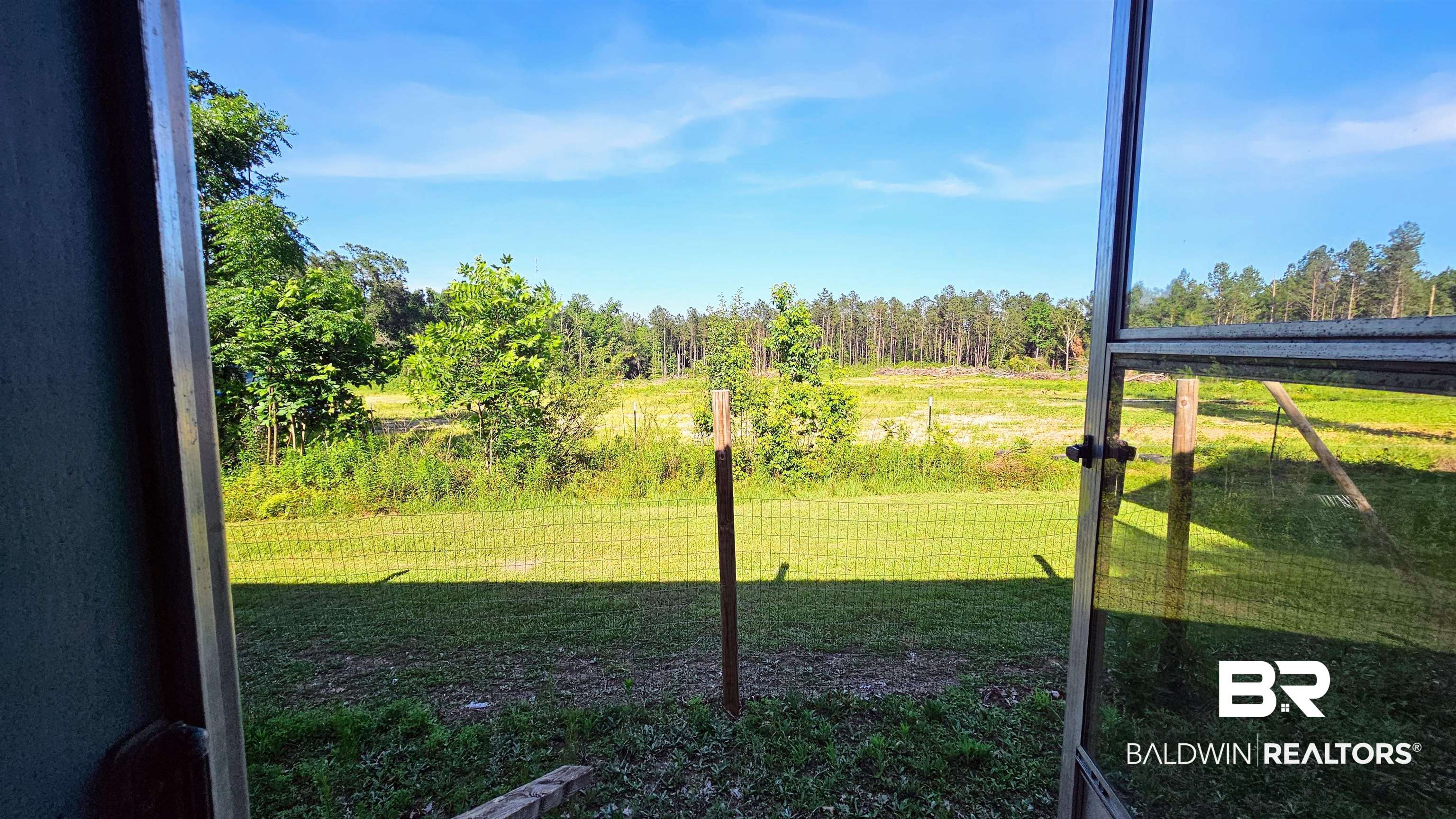 18824 Highway 41 Brewton, AL 36426 - Photo 9 of 40 Expansive outdoor space featuring a large grassy area, partial wire fencing, and a distant tree line