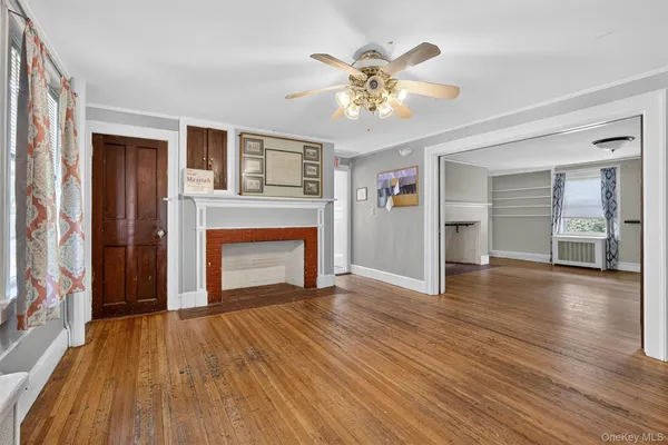 a view of an empty room with wooden floor and a fireplace