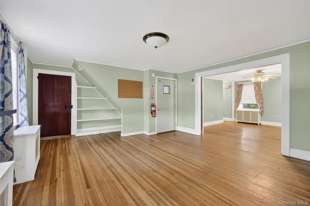a view of an empty room with wooden floor and a window