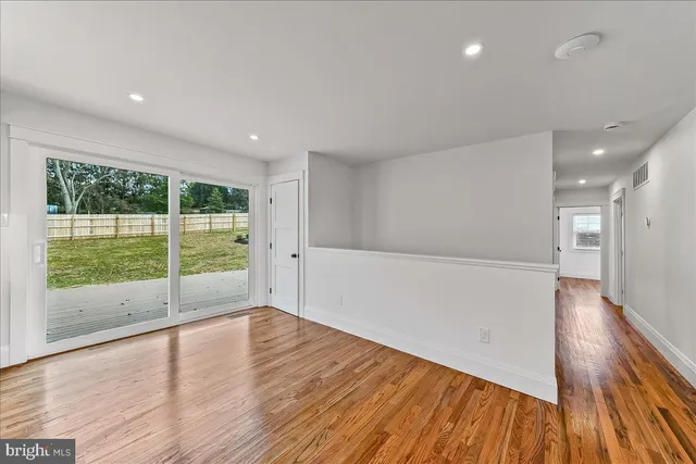 an empty room with windows and ceiling fan