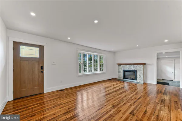 a view of an empty room with wooden floor fireplace and a window
