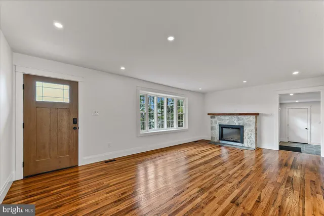 a view of an empty room with wooden floor fireplace and a window