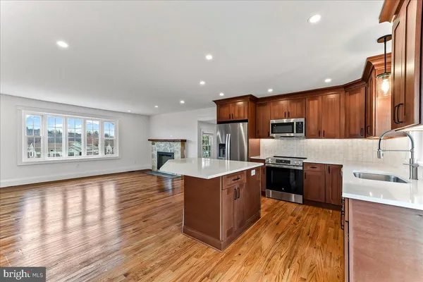 a large kitchen with stainless steel appliances granite countertop a stove a sink dishwasher and a refrigerator with wooden floor