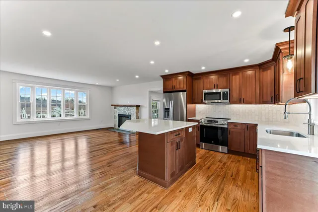 a large kitchen with stainless steel appliances granite countertop a stove a sink dishwasher and a refrigerator with wooden floor