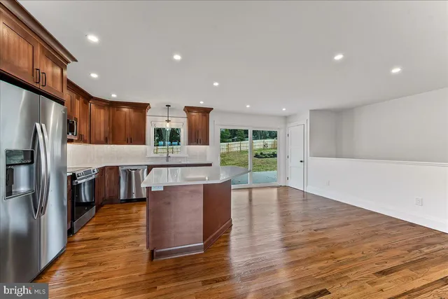 a kitchen with stainless steel appliances a refrigerator and a wooden floor